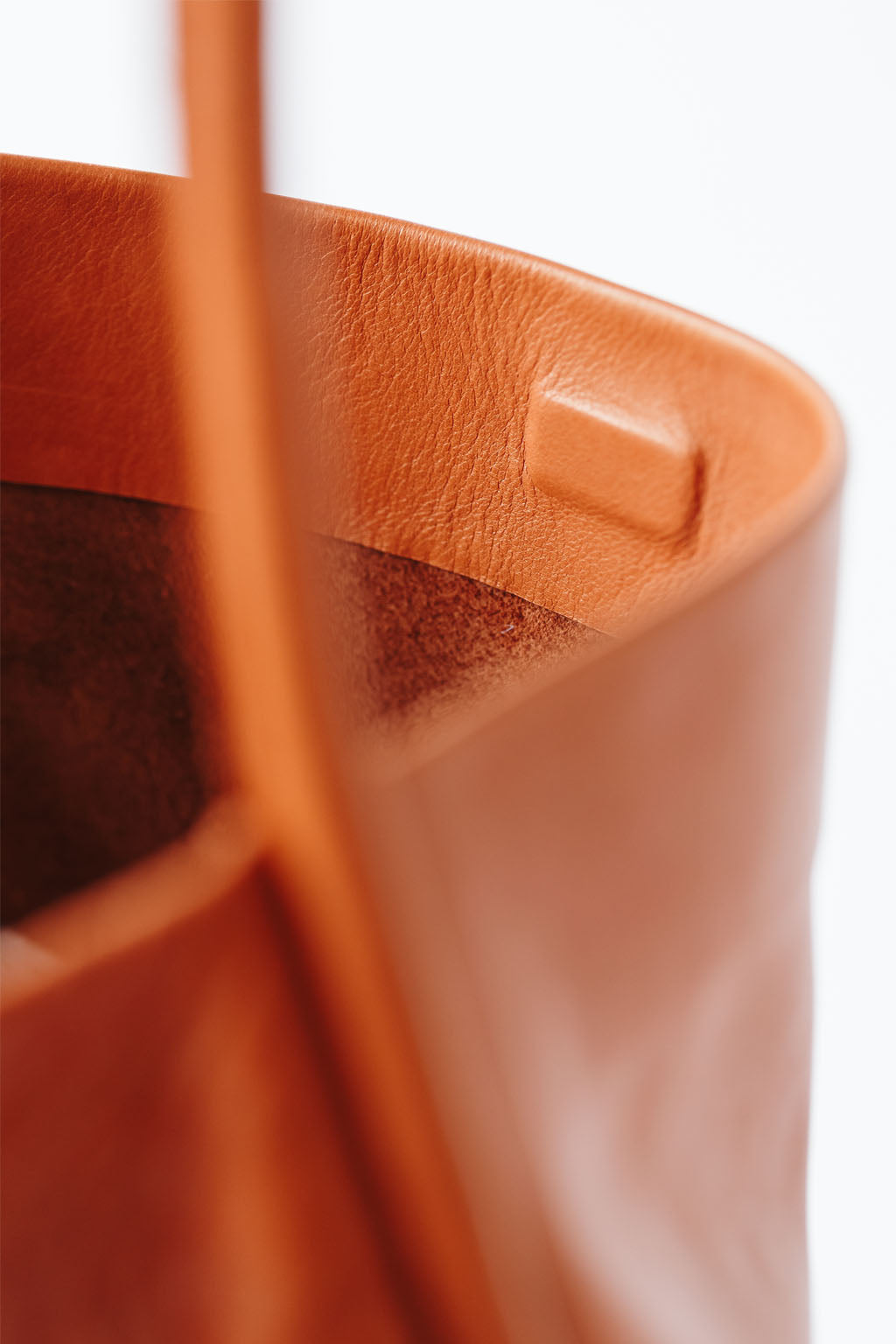 A detail of a cognac leather shoulder bag's magnetic closure, showing the interior of the bag.