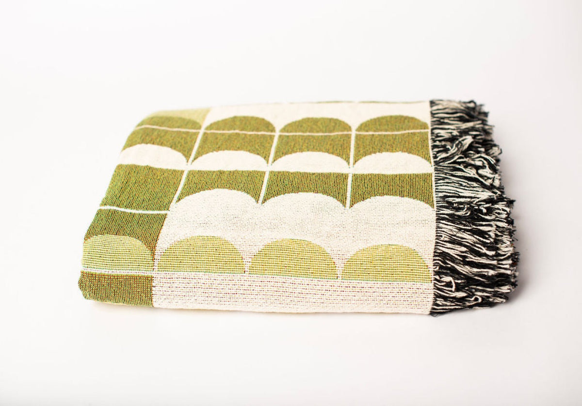 Close-up of Quinn Meadow green, gold, and cream geometric scallop jacquard woven blanket with fringe