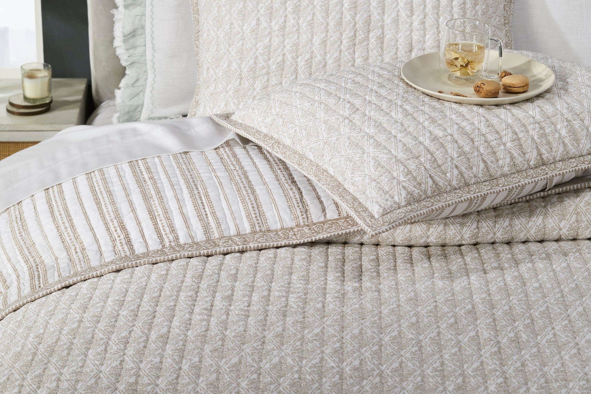 QT-348-9496_5|Elegant cream quilt with detailed gold geometric patterns and matching ruffled pillows on a bed, providing comfort and style.