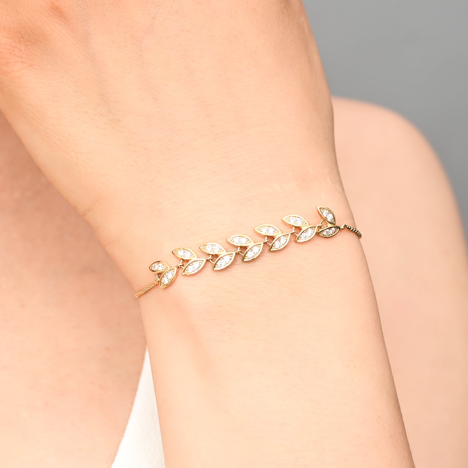 Photo of gold bracelet on woman, golden leaf bracelet, fair trade jewelry business for women, quality christmas gift ideas 