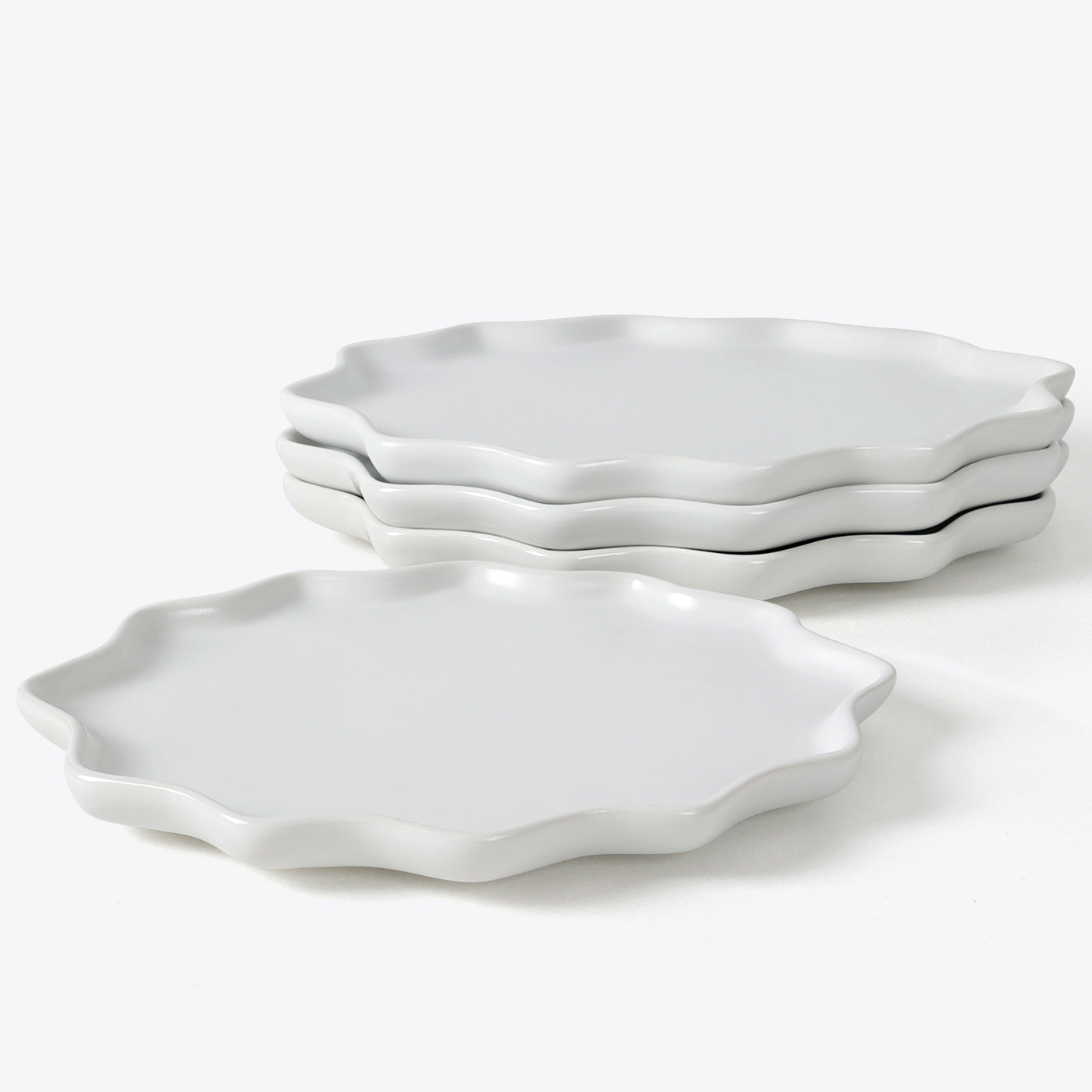 Set of white ceramic plates with scalloped edges on a white background