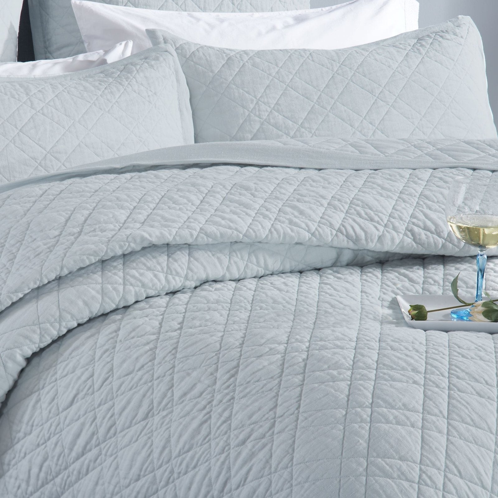 CL-255-11096_4|Elegant light blue quilted coverlet on a bed with matching pillows and a drink. Creates a serene and luxurious retreat.