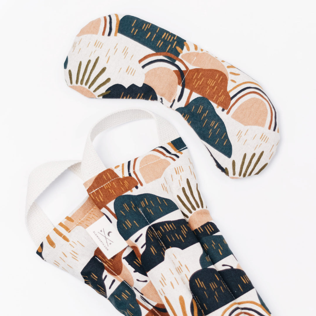 Dark blue mountains with rainbow and sun patterns of assorted rust, brown, orange, and olive colors on cream fabric. 