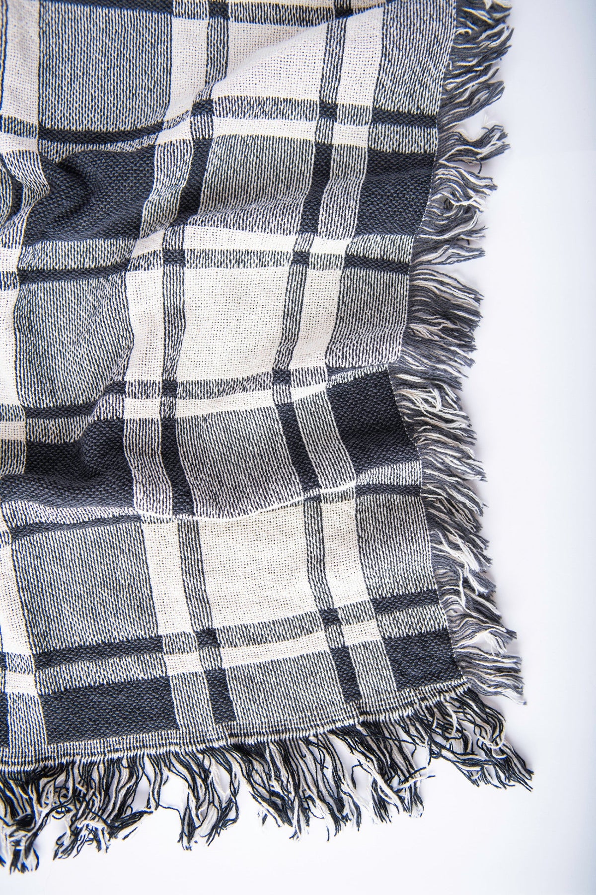 Close-up of Ellis black-and-white plaid woven throw arranged to show its reversible pattern and fringe