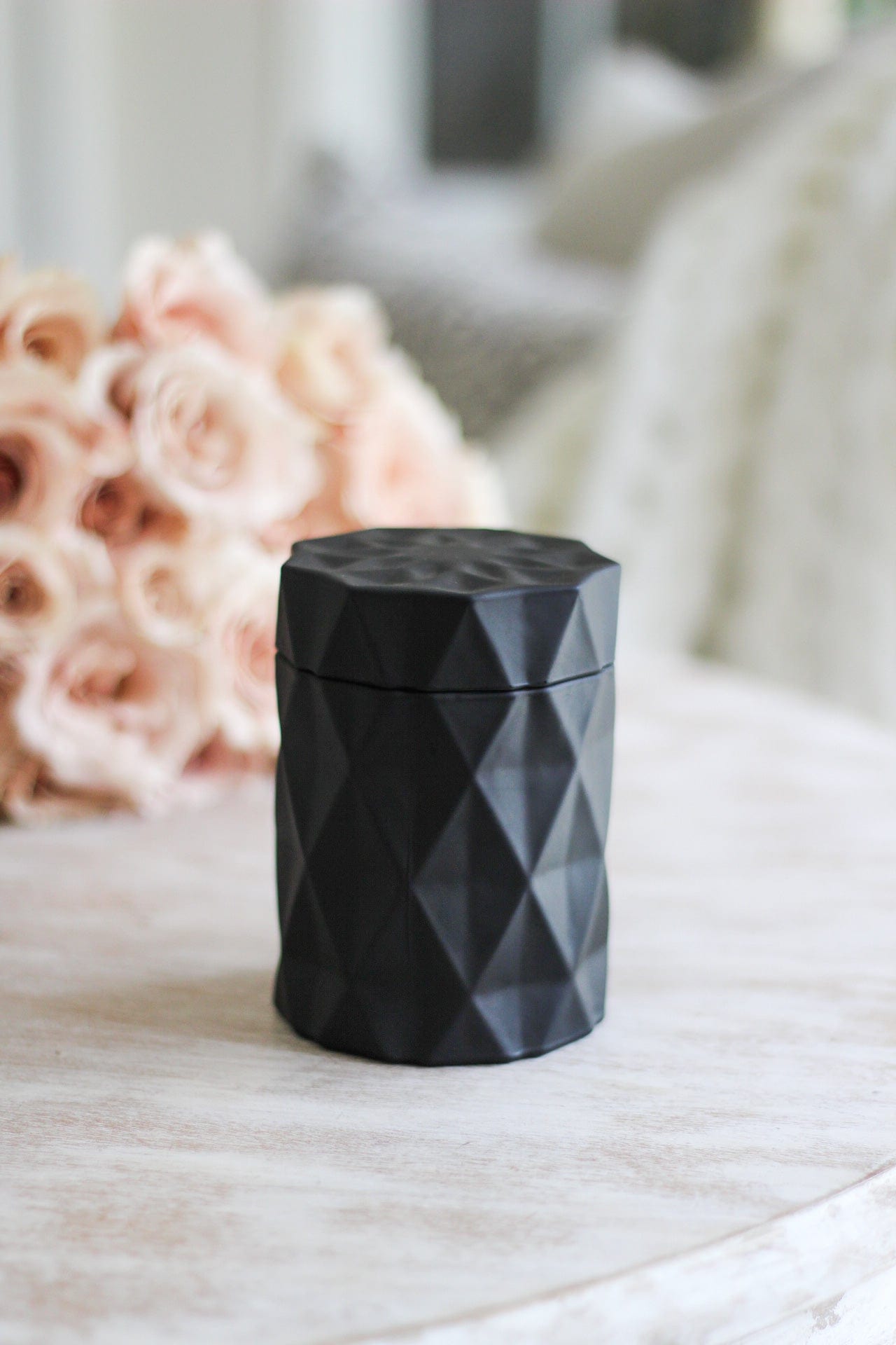 matte black candle jar next to pink rose bouquet on coffee table decor