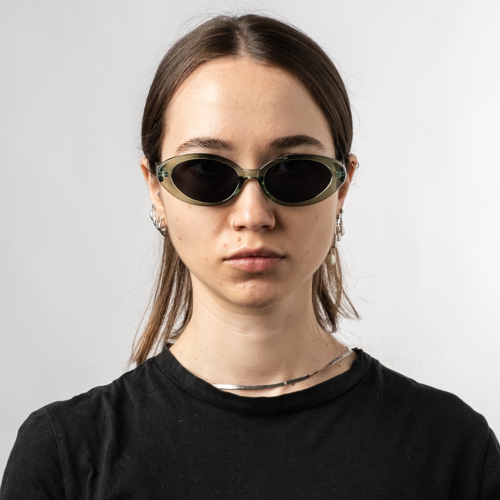 Female wearing Sad Eyewear Bloom oval sunglasses in sea glass green with tinted black lenses
