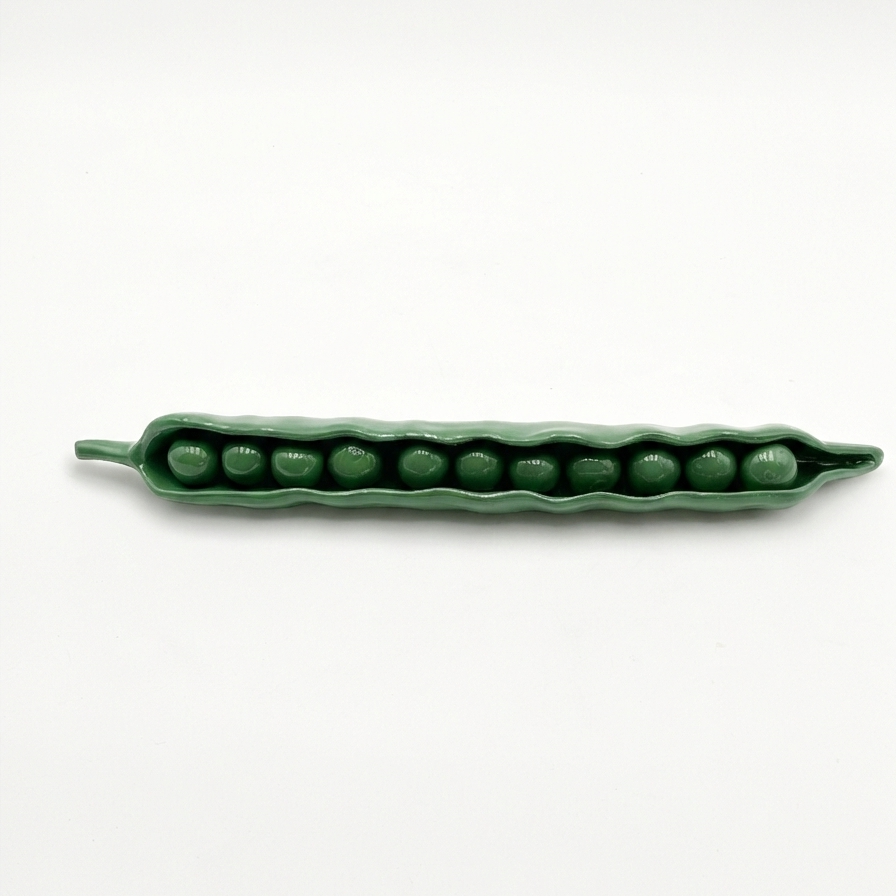 Green ceramic pod with peas on a white background