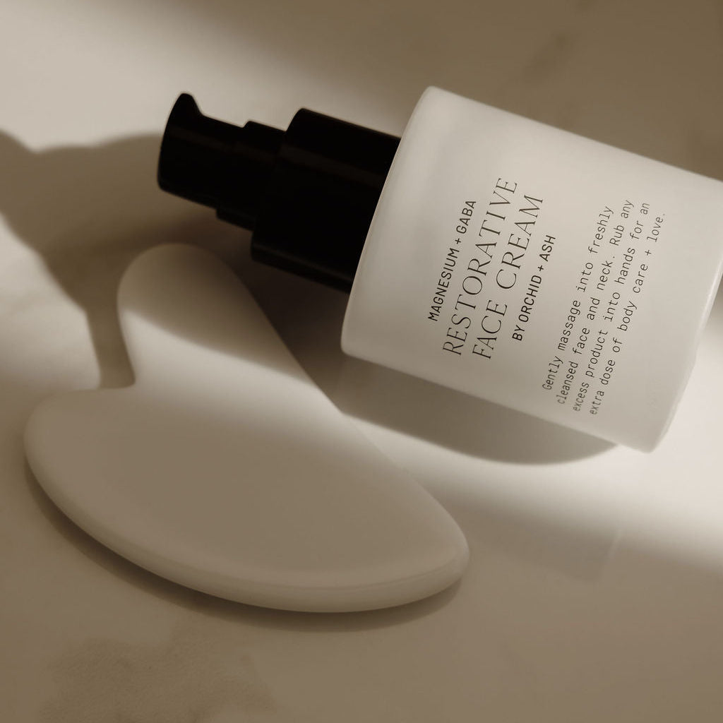White face cream bottle with black cap on a marble surface