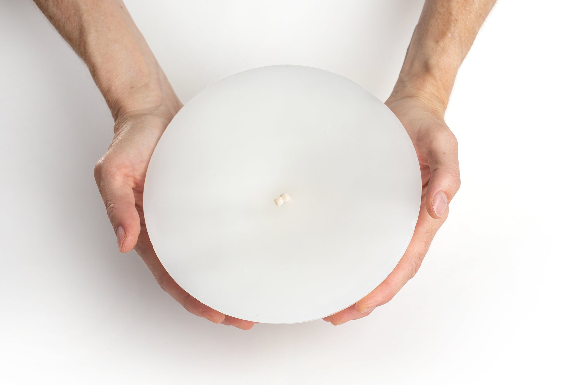 Hands holding a Luma Afrika Outdoor Bowl candle 6.75" width that shows that it is slightly larger then sitting in the palms of your hand.  Infused with citronella & lavender to repell inscects.  