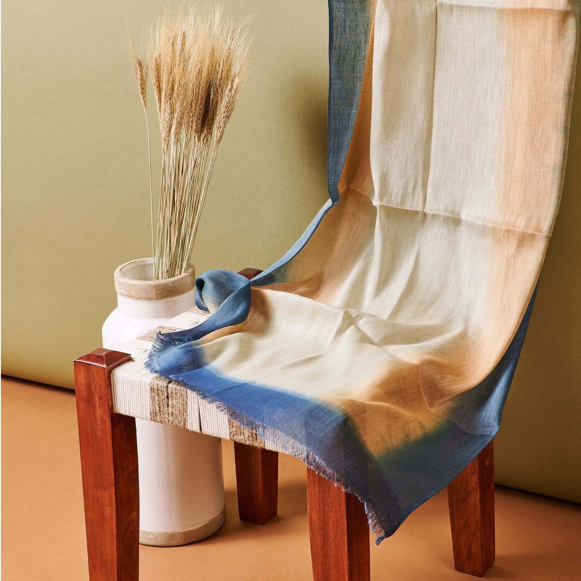 Oceana Beige Soft Linen Silk Handloom Scarf displayed on a wooden chair with decorative vase and dried flowers.
