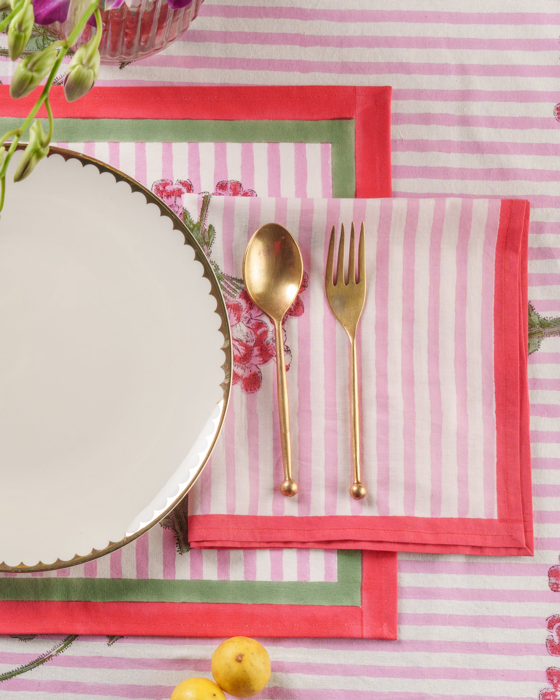 Pink striped napkin with gold utensils on decorative table setting