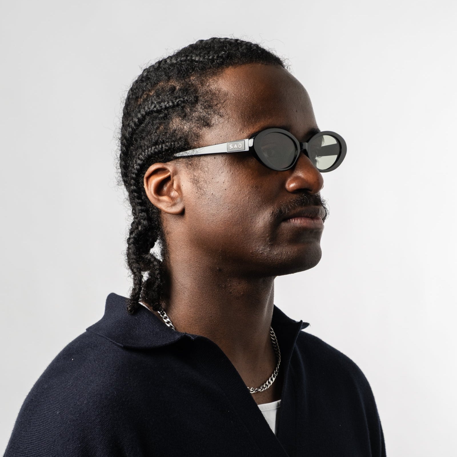 Male wearing Sad Eyewear Bloom oval sunglasses in black with tinted olive lenses