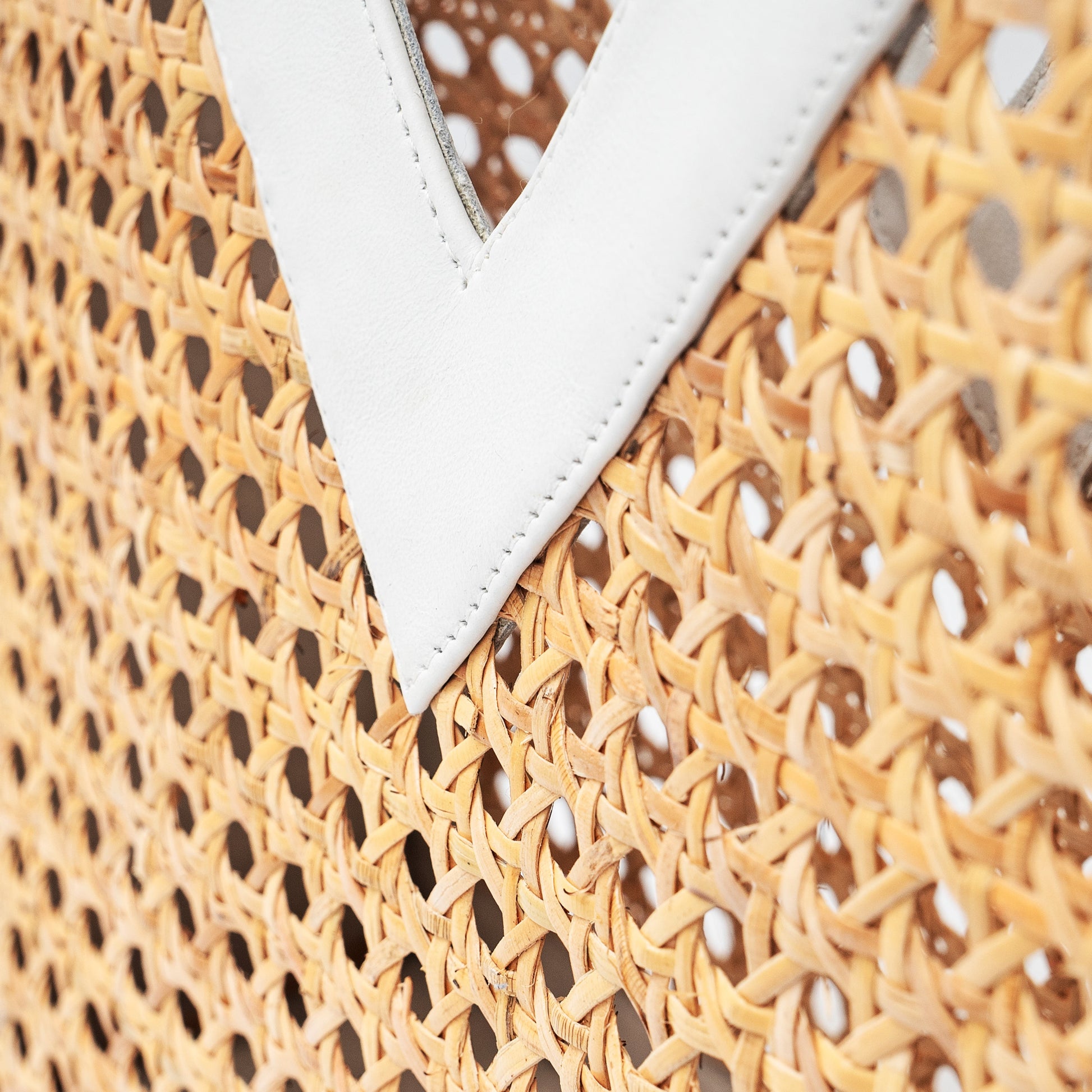 Detail up close view white leather trim and cane webbing rattan top handle tote handbag