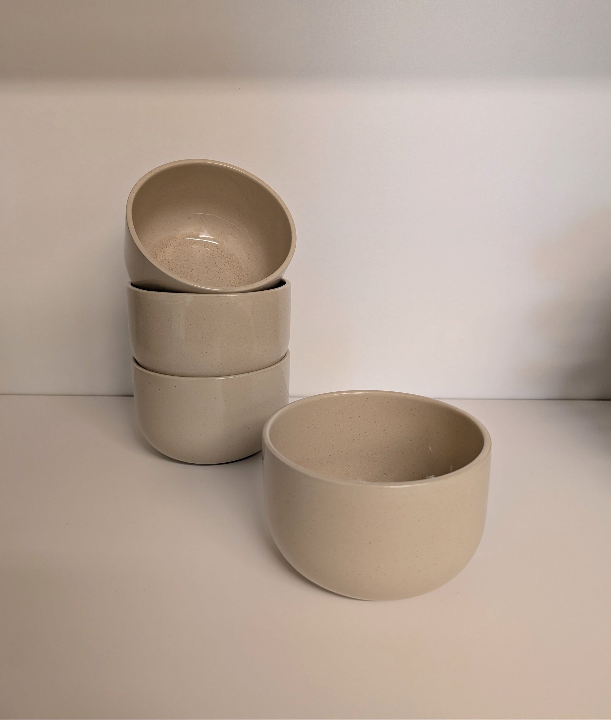 Set of three beige ceramic bowls on a white surface with a white background