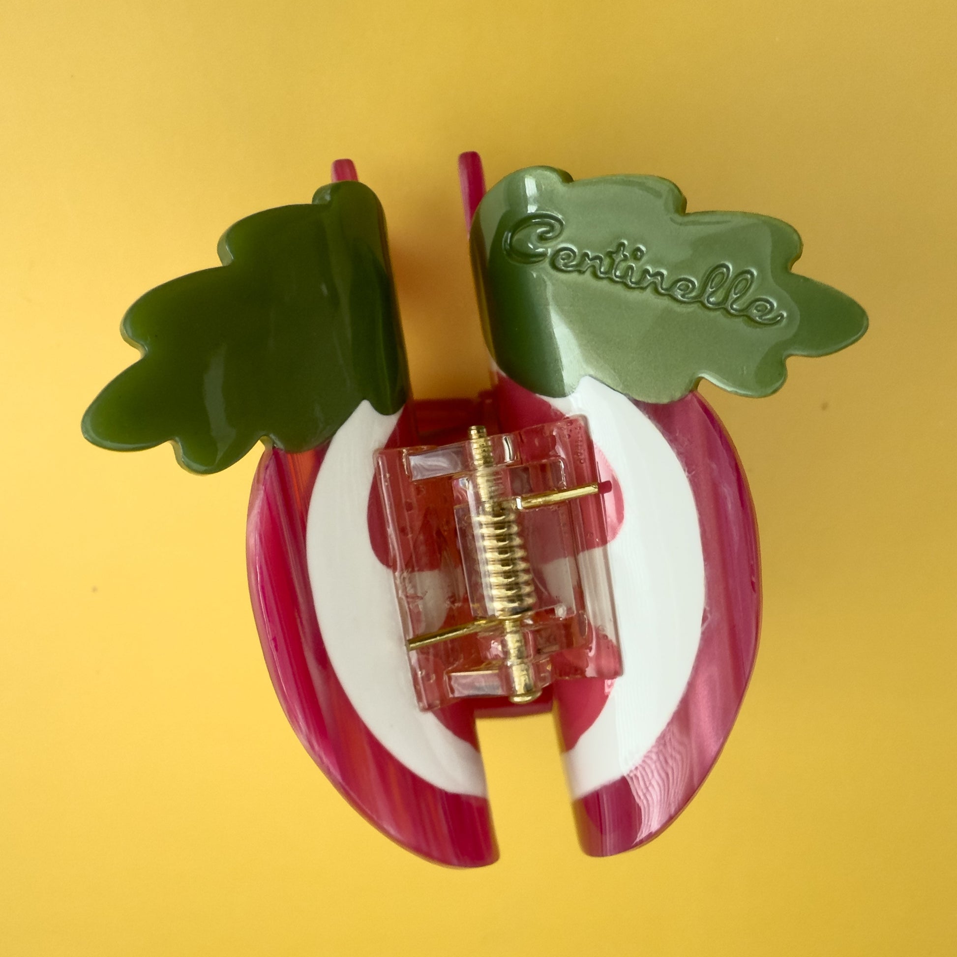 Decorative pomegranate hair claw with a green leaf. Don't let this tough exterior fool you! Beneath its rosy glow lies a treasure chest of tiny, ruby-red jewels, each one a delightful explosion of sweet-tart goodness.

Pomegranate hair claw season is here and we can help but wearing it too!