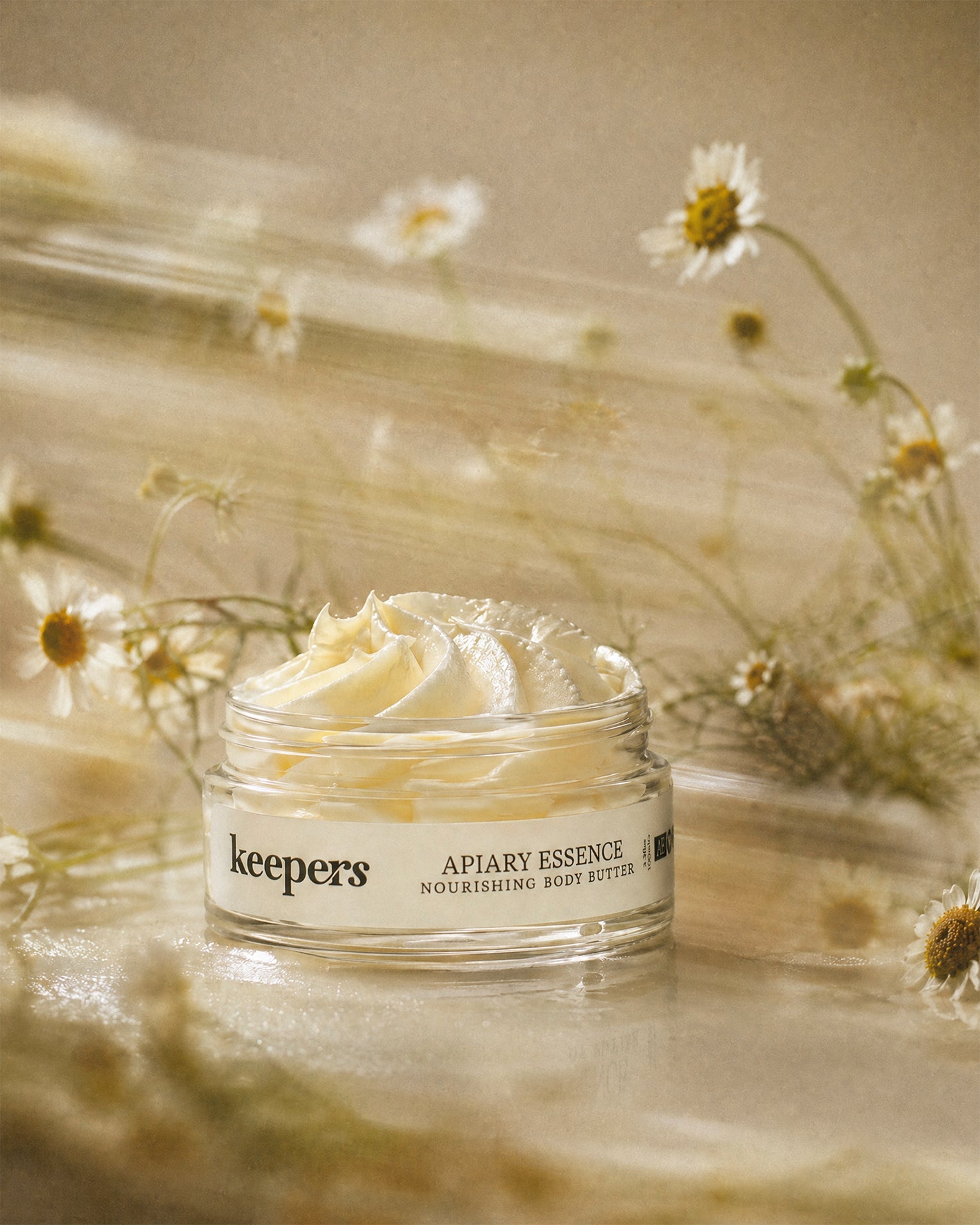 Jar of 'keepers Apiary Essence' body butter with flowers in the background