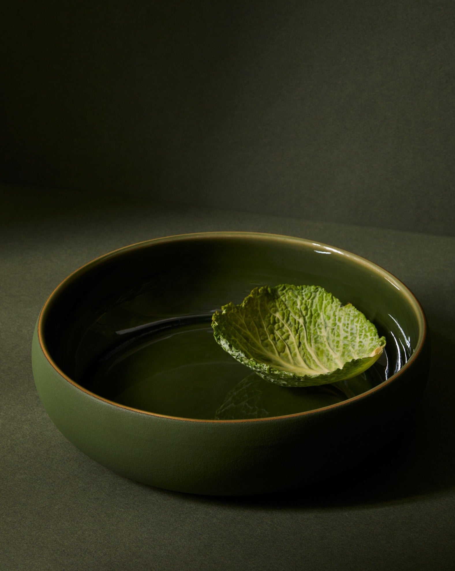 A beige Stoneware Shallow Serving Bowl with a capacity of 60 oz, displayed against a neutral background with a small amount of food items like pasta or noodles in it to showcase its size and shape.