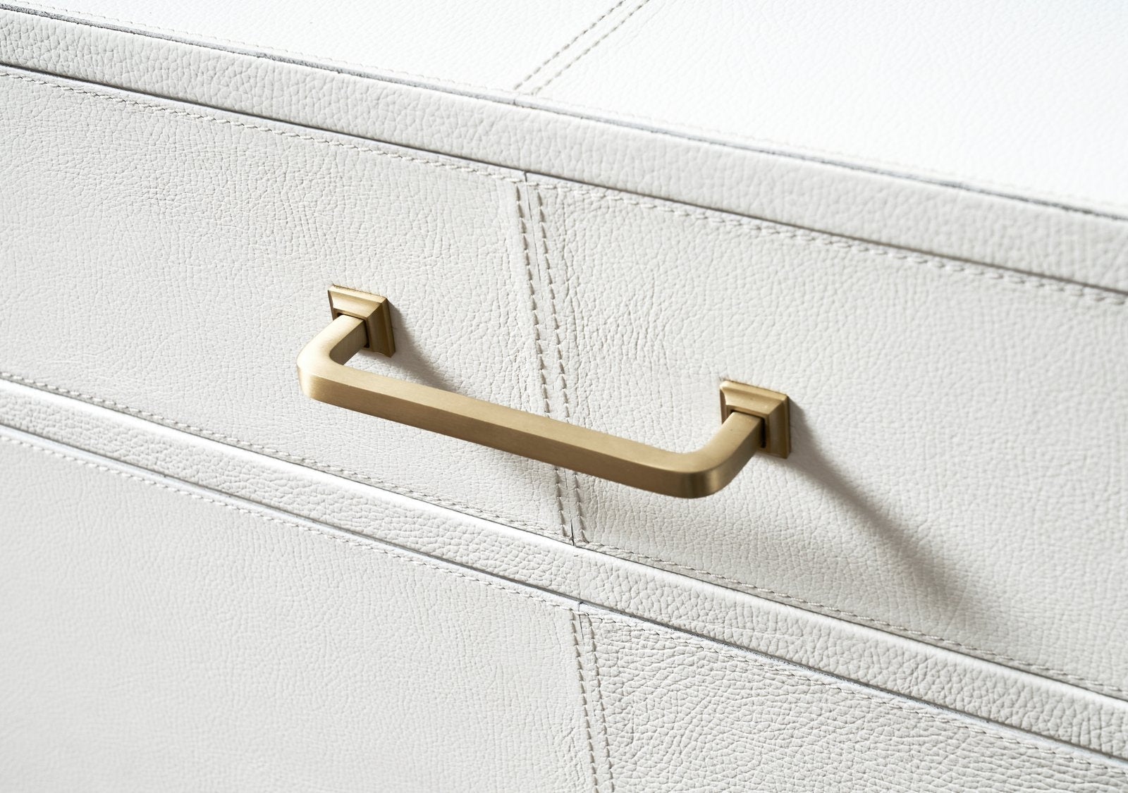 FN-5201-642033_5|Close-up of a sophisticated gold bar pull handle on a white genuine leather dresser, showcasing luxury furniture detail.