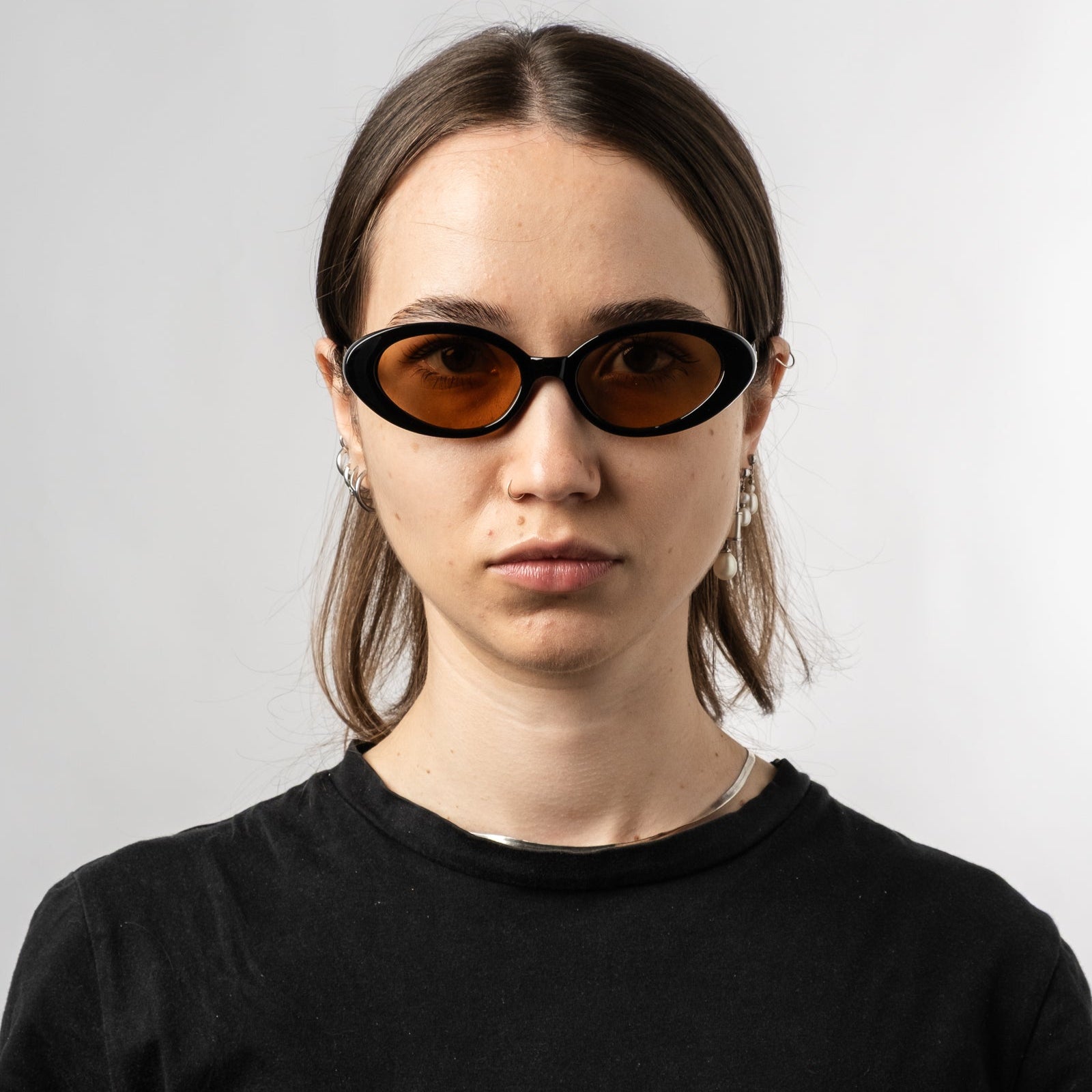 Female wearing Sad Eyewear Bloom oval sunglasses in black with tinted bronze lenses