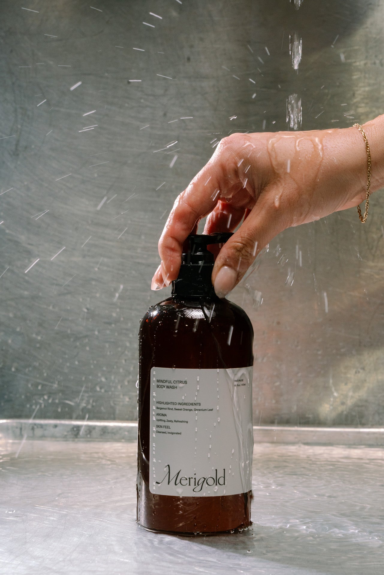 Hand holding Merigold body wash against a reflective surface.