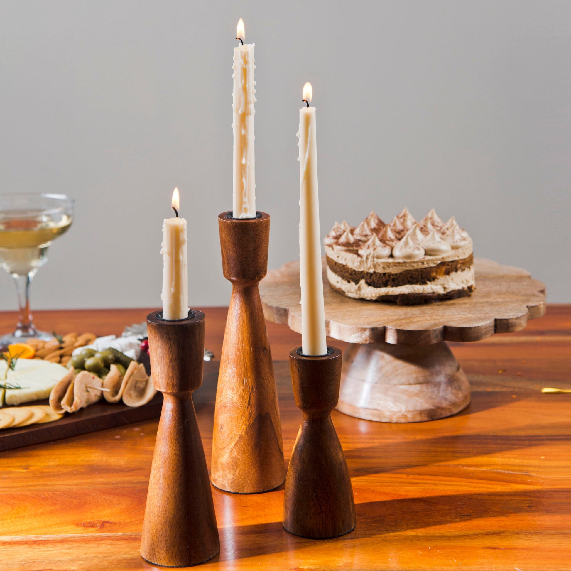 Handcrafted natural brown mango wood candlesticks with white taper candles set against a clean white background.