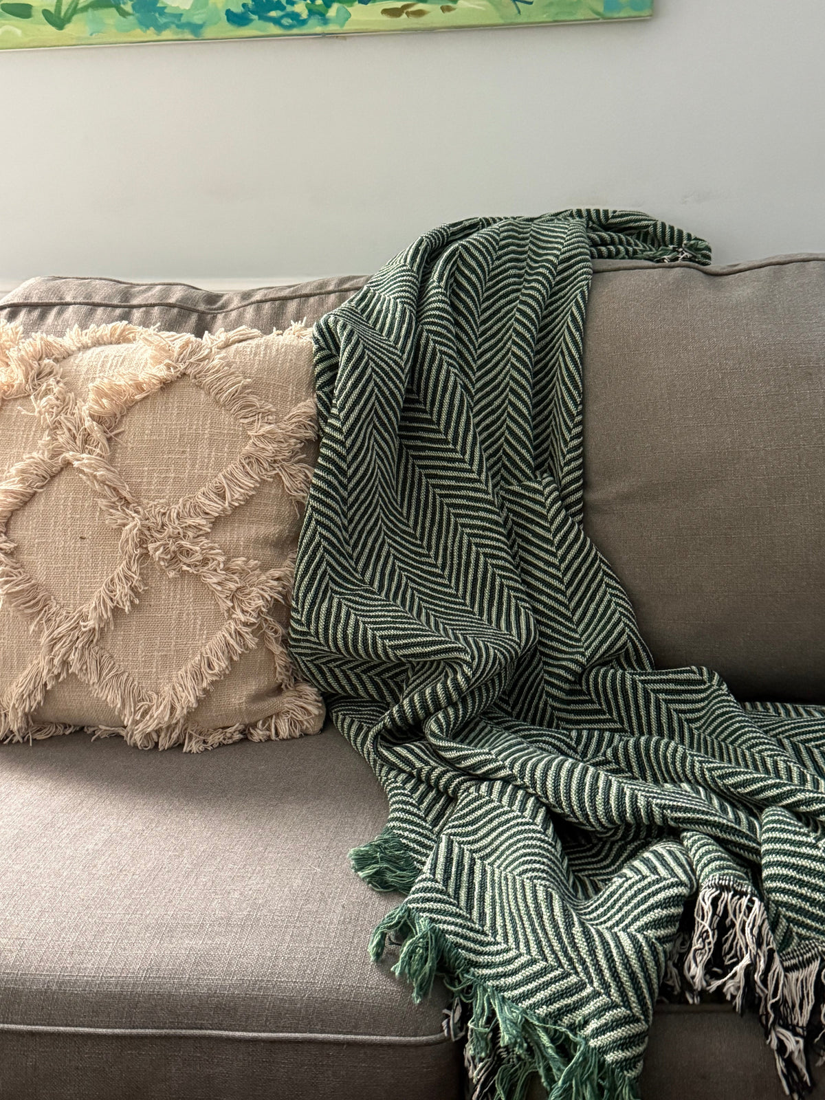 Folded mustard yellow and neutral herringbone blanket on a light background