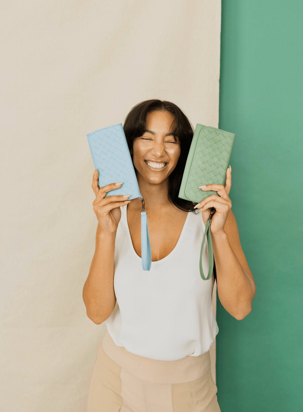 Woman holding sky blue & sage green wristlet wallets