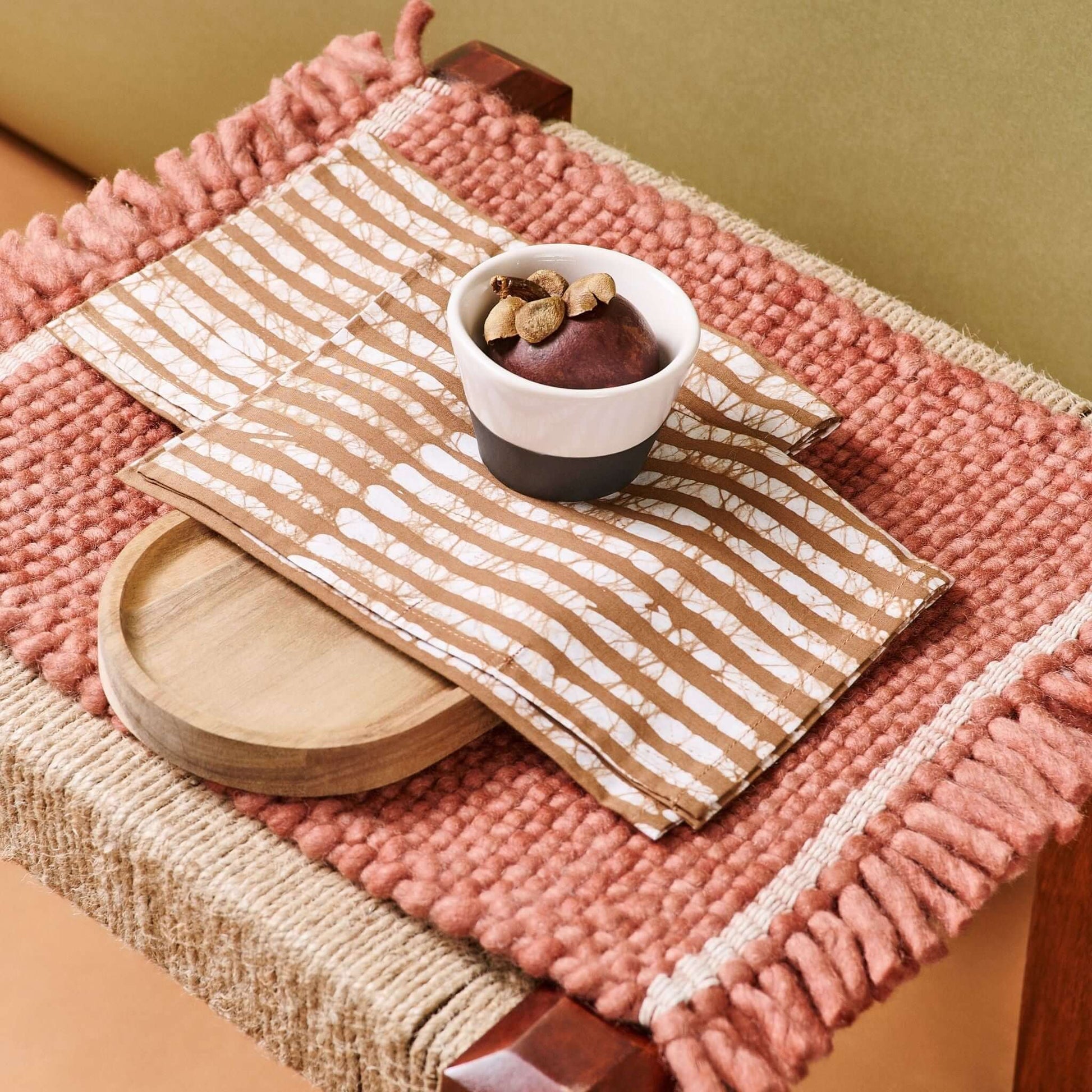 Oak Brown Stripes Wax Block Print Cotton Table Napkin set of 4 displayed on a textured surface with a bowl of snacks.