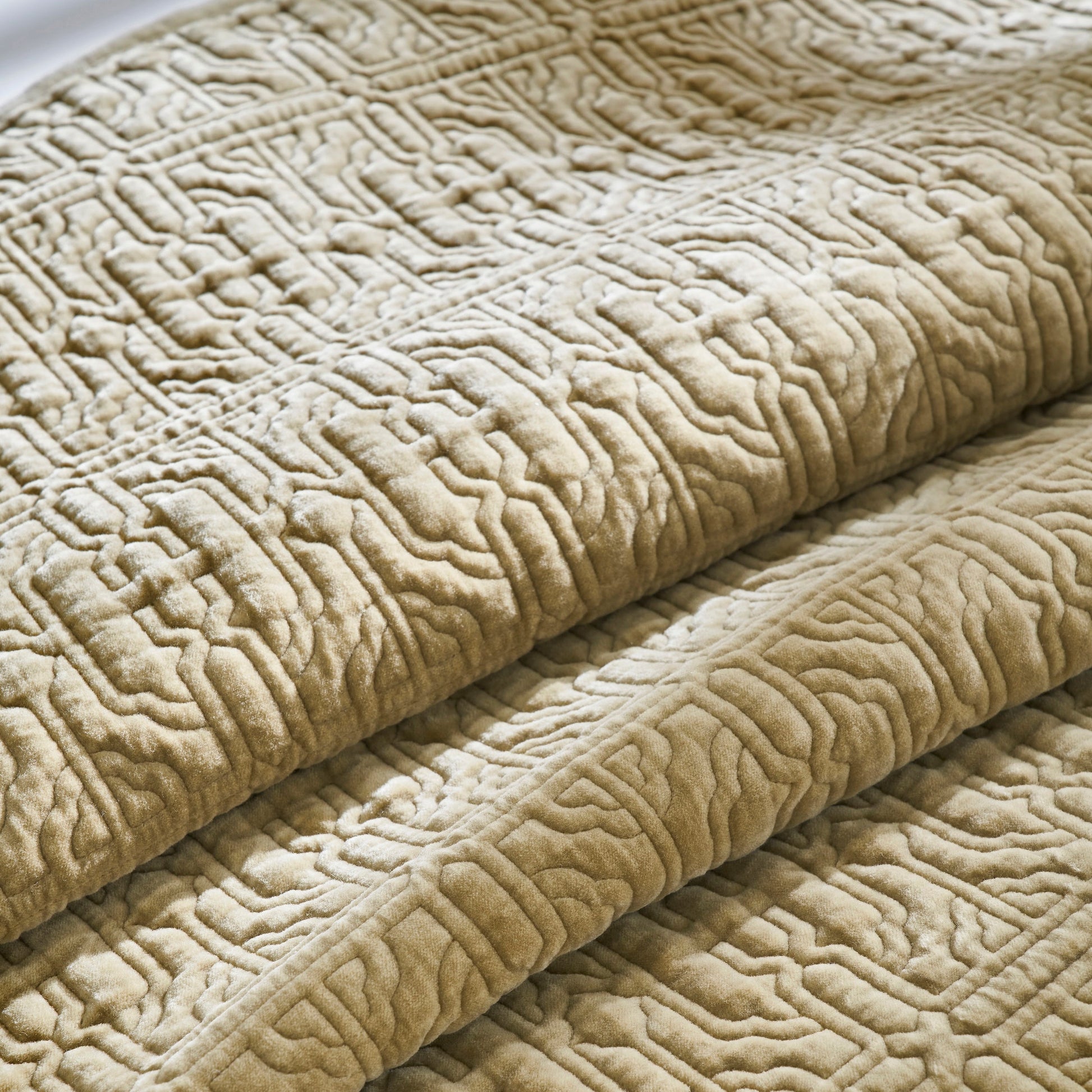 QT-377-11096_6|Close-up of a folded plush tan quilt, showcasing its intricate geometric pattern and soft, textured fabric for cozy comfort.