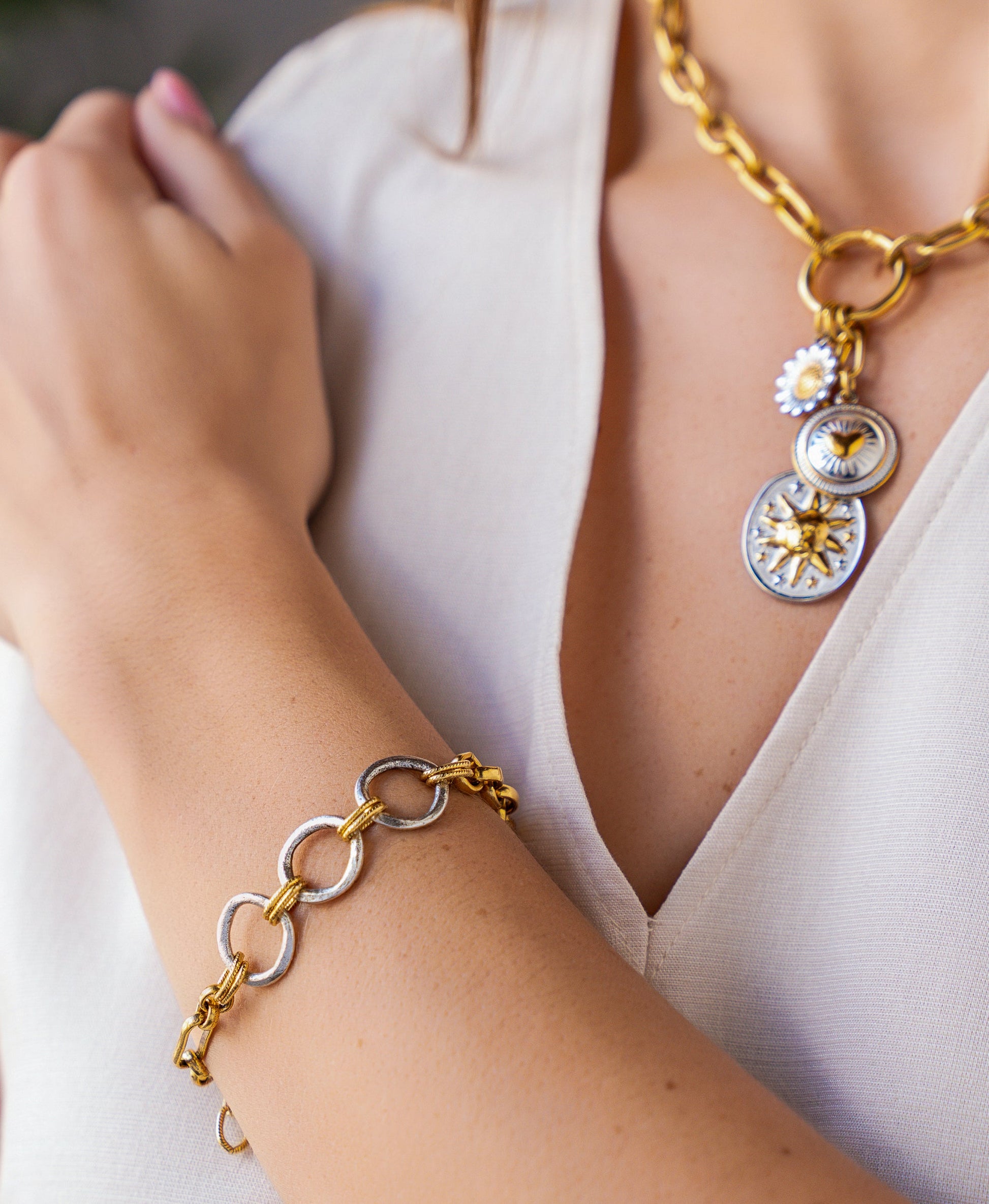 Mixed metal bracelet with oversized gold and silver rings connected by twisted rope links and chain details.