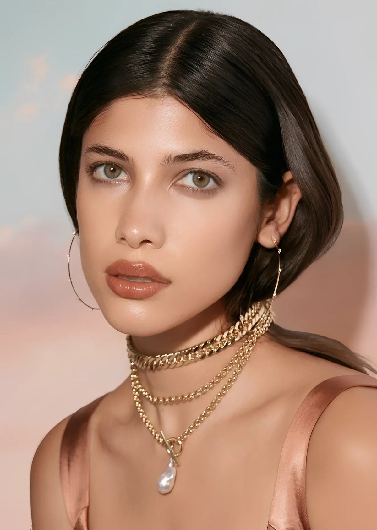 Woman wearing layered gold necklaces with baroque pearl pendants and toggle clasps