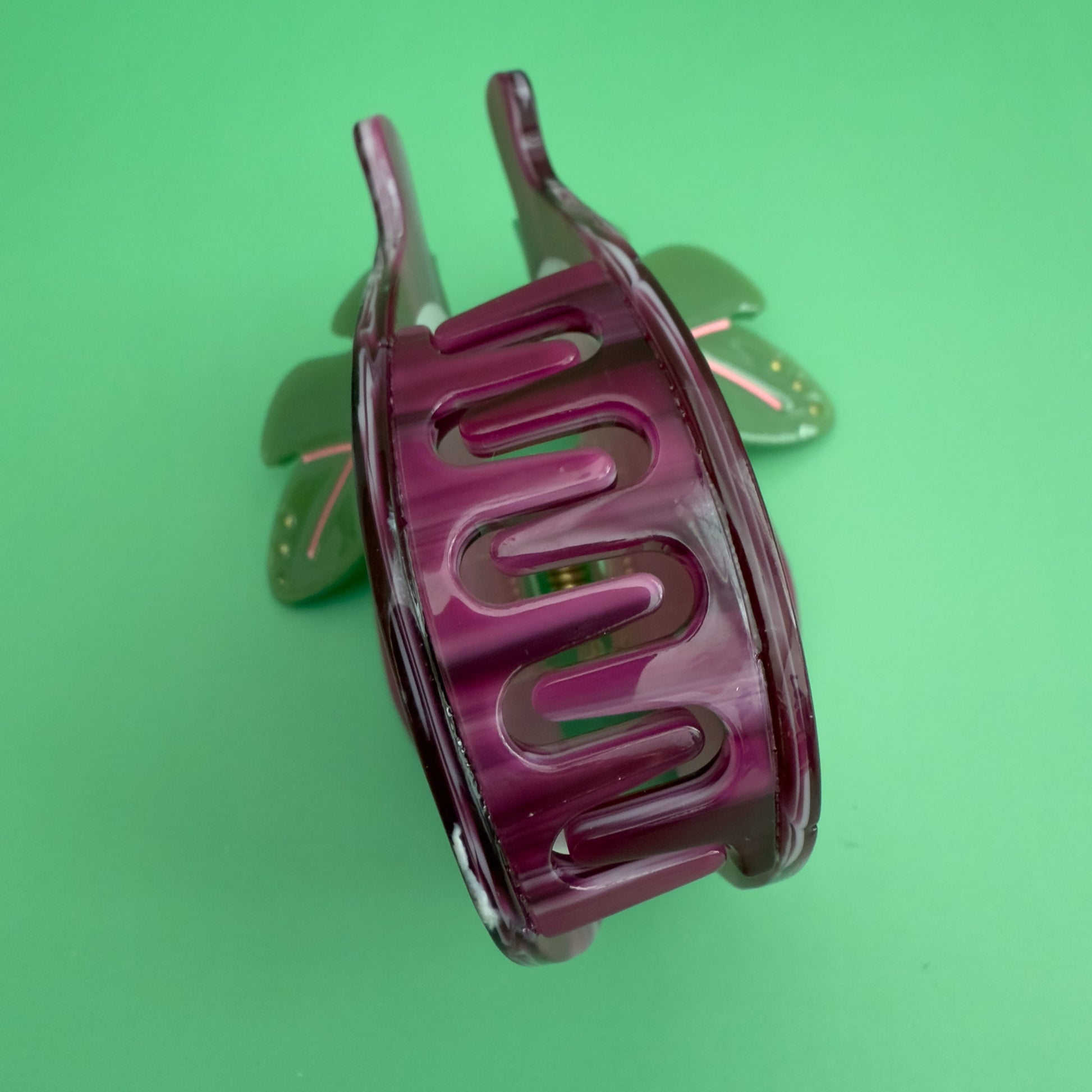 Decorative hair claw like a sliced fig on a green background. 