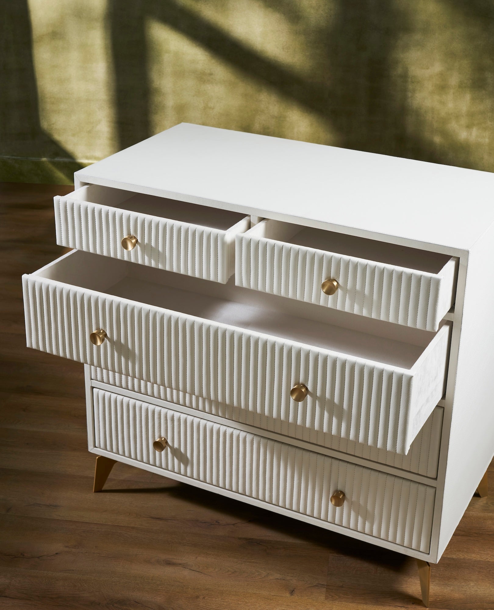 FN-5216-482036_4|Close-up of white ribbed leather dresser with open top drawers and elegant gold hardware, showcasing luxury storage detail.