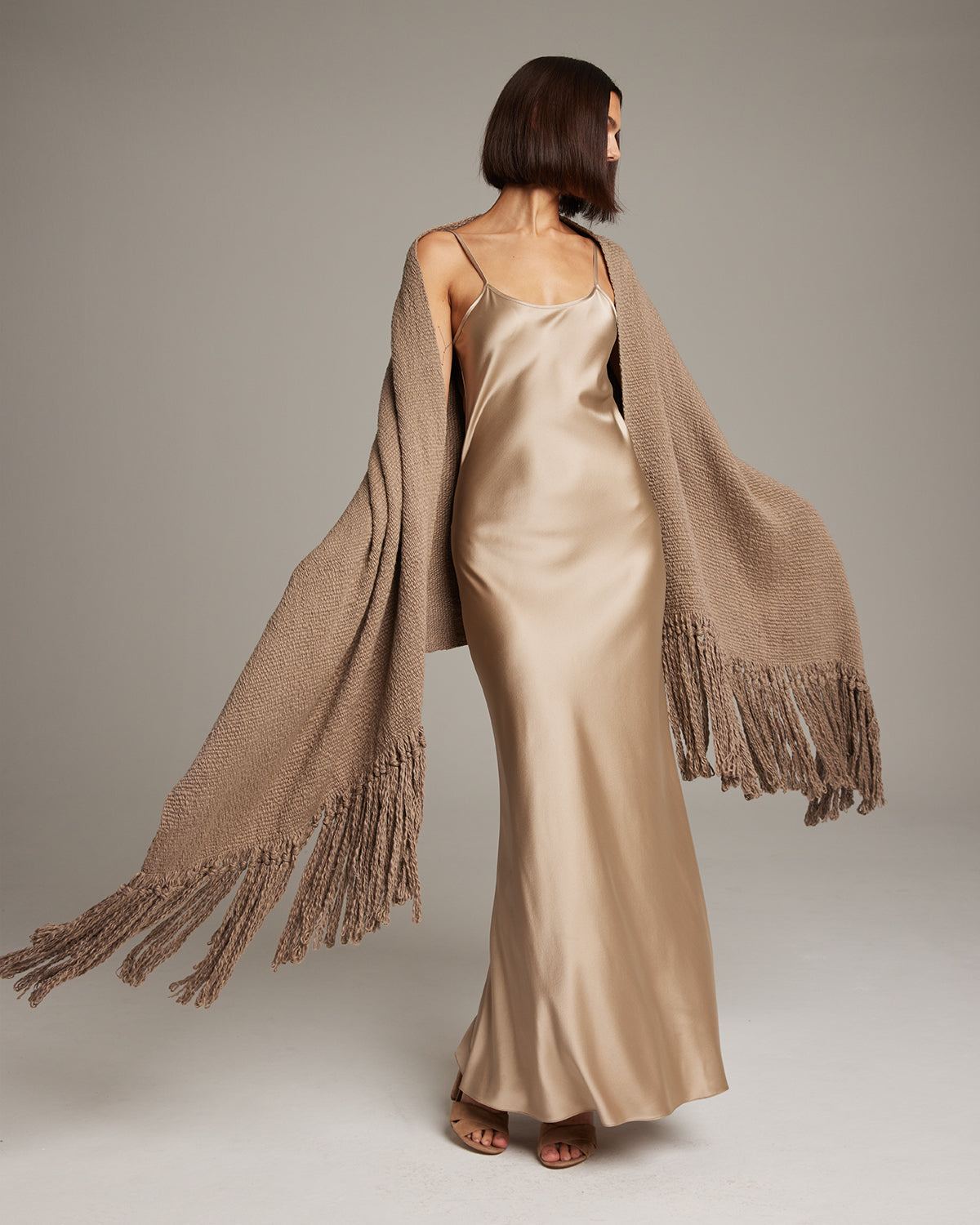 Model wearing a Flammé Fringe Wrap shawl with fringes, styled with a satin dress.