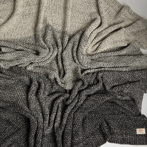 Close-up of a textured gray gradient throw blanket with a Pink Lemonade brand label.