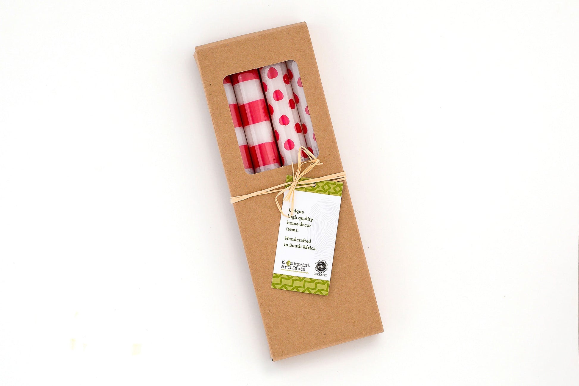 Kraft gift box of 4 taper candles; two red stripe on white and two red dot on white.  Tied with a story card.  Fair Trade, hand crafted.