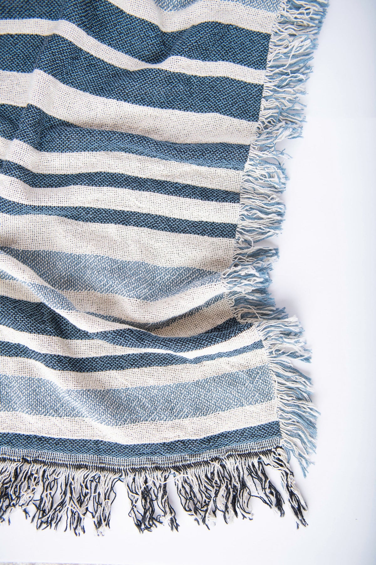 Close-up of Sutton Delft blue and cream coastal stripe woven cotton blanket with fringe