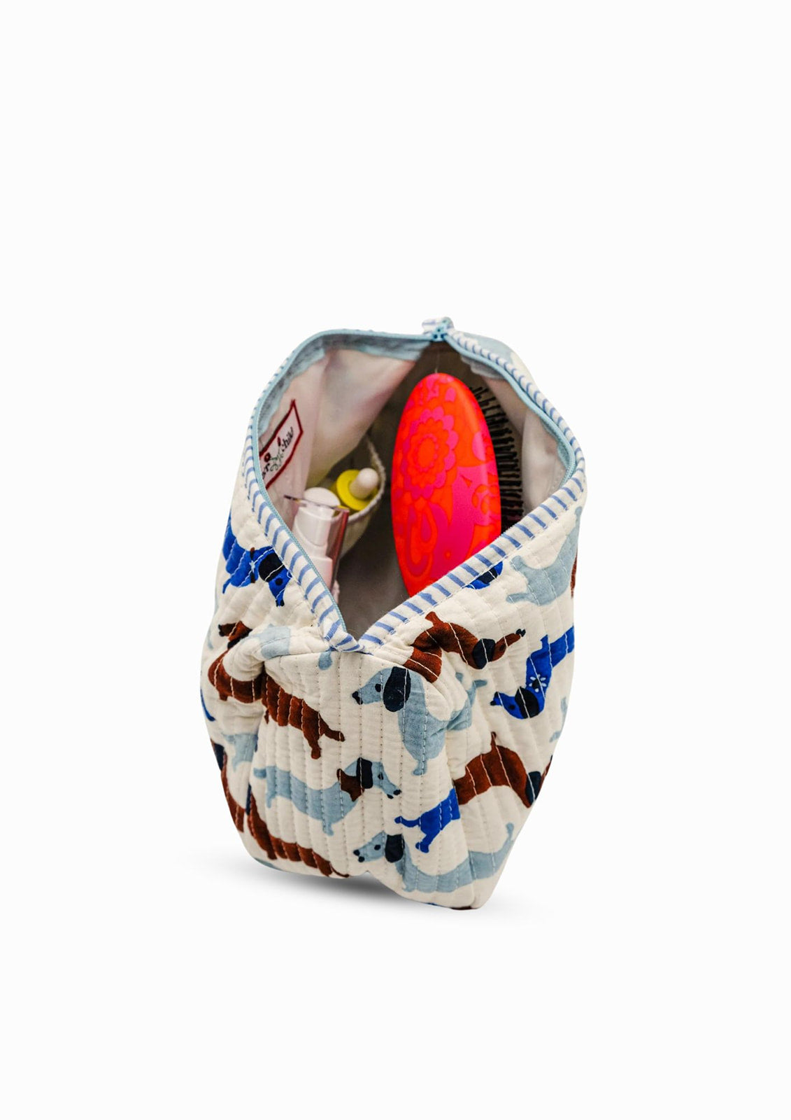 Open dashing doxies toiletry bag with colorful dachshund pattern holding brush and accessories