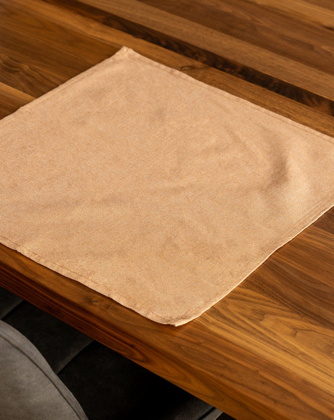 A Copper cotton placemat is laid out on a wooden table.