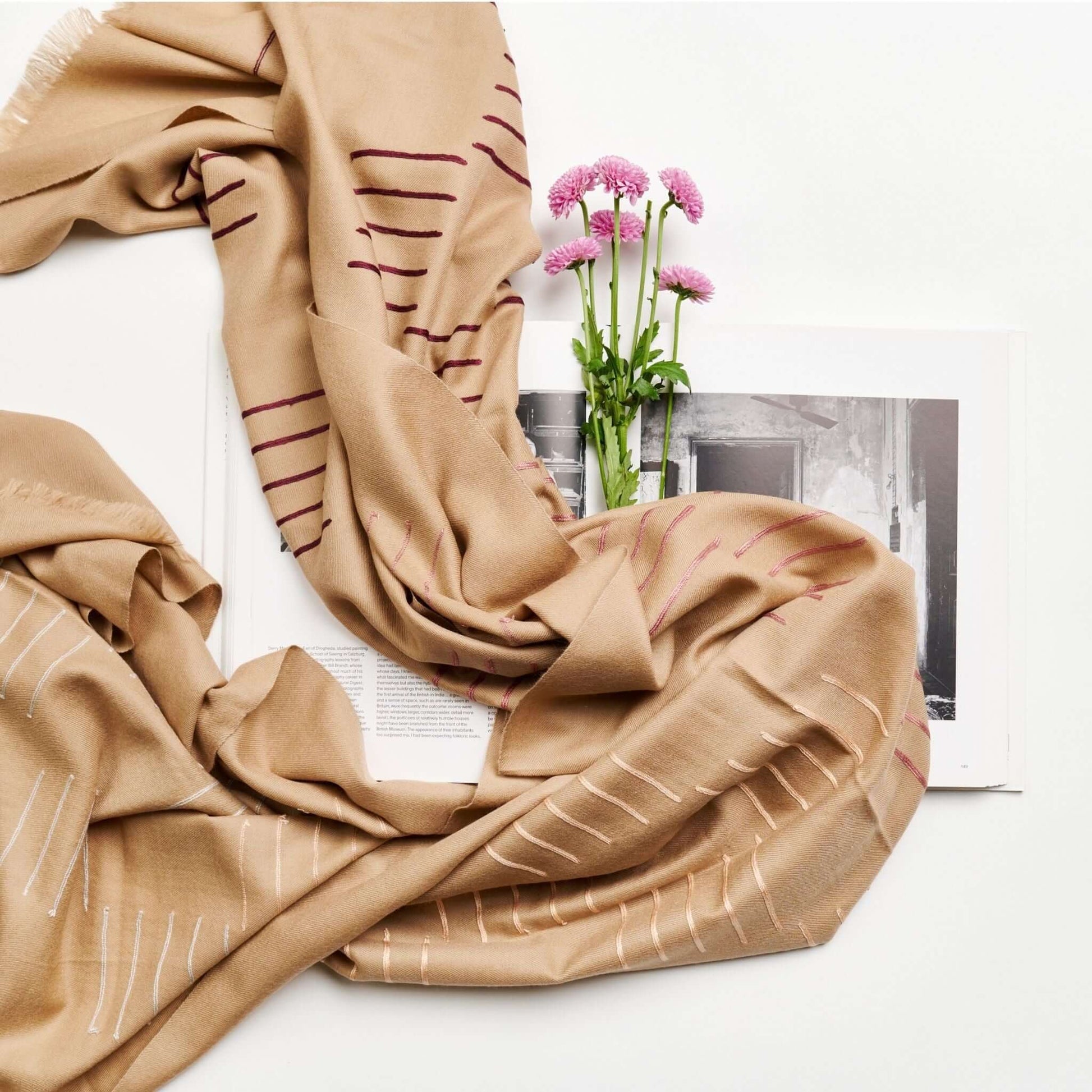 Maple Beige Handwoven Hand Embroidered Classic Scarf displayed with flowers and a book on a white background.