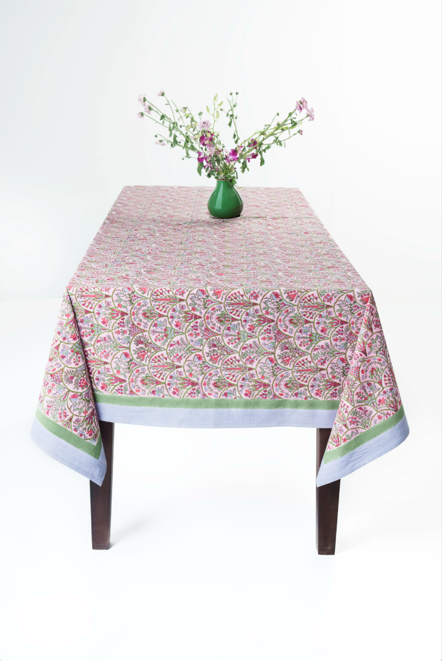Pink Arch blockprint tablecloth draped over wooden table with green vase