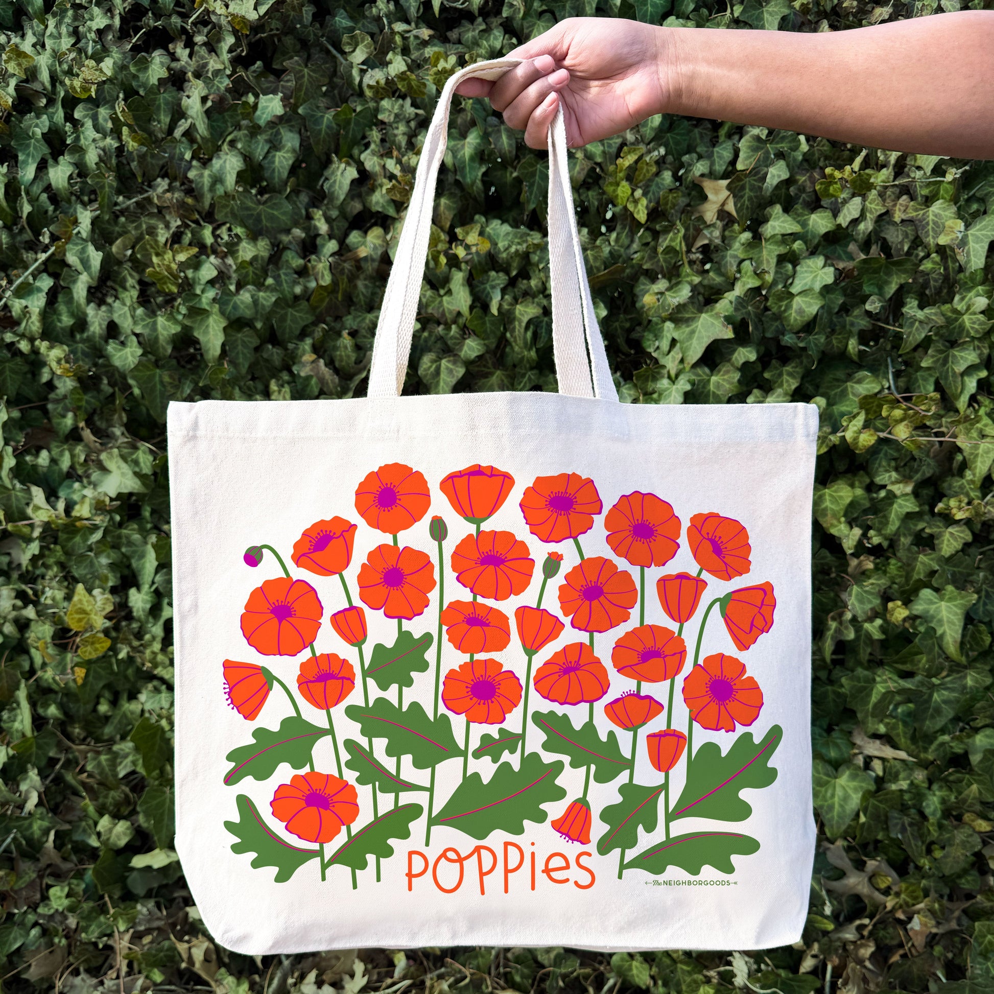 A woman holds the Poppies tote bag.