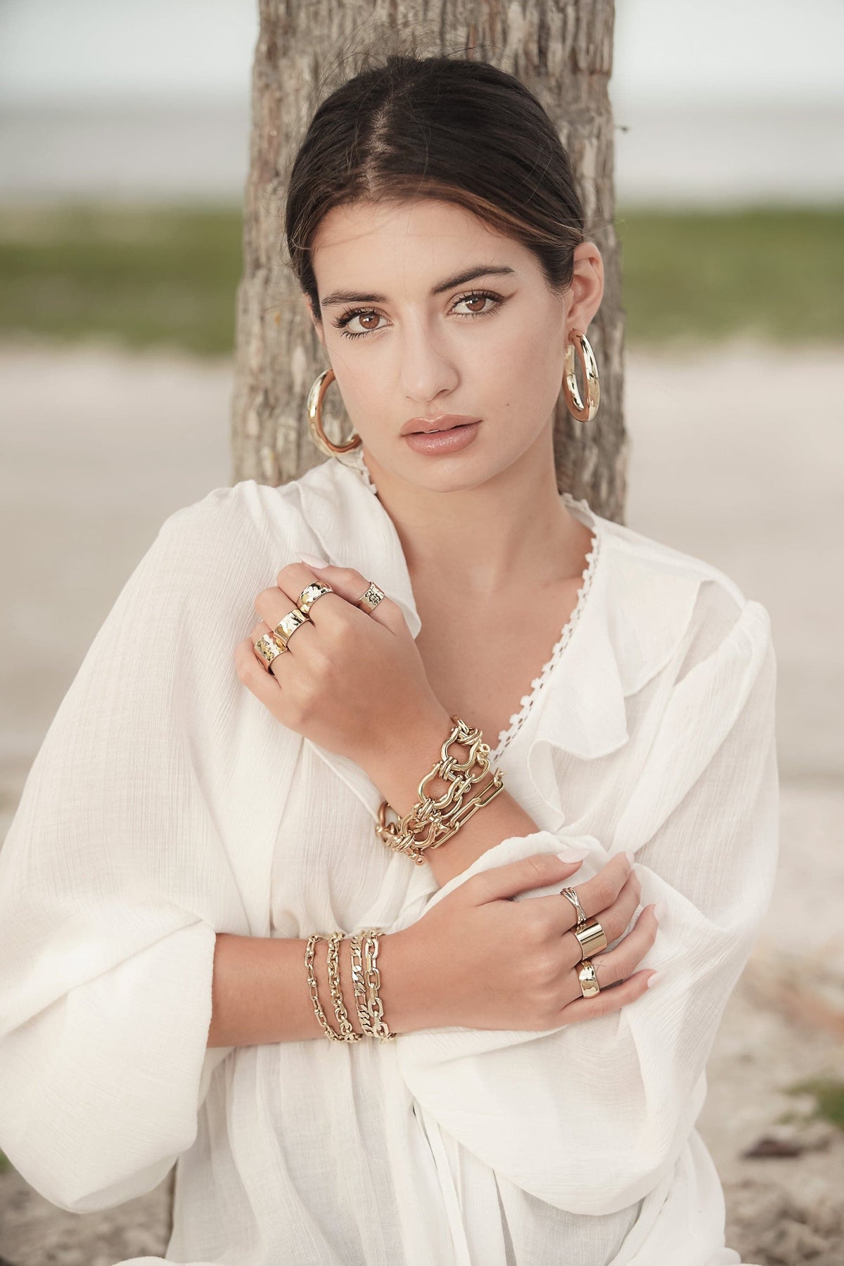 Woman showcasing Lennon Bracelet with stylish gold jewelry setup