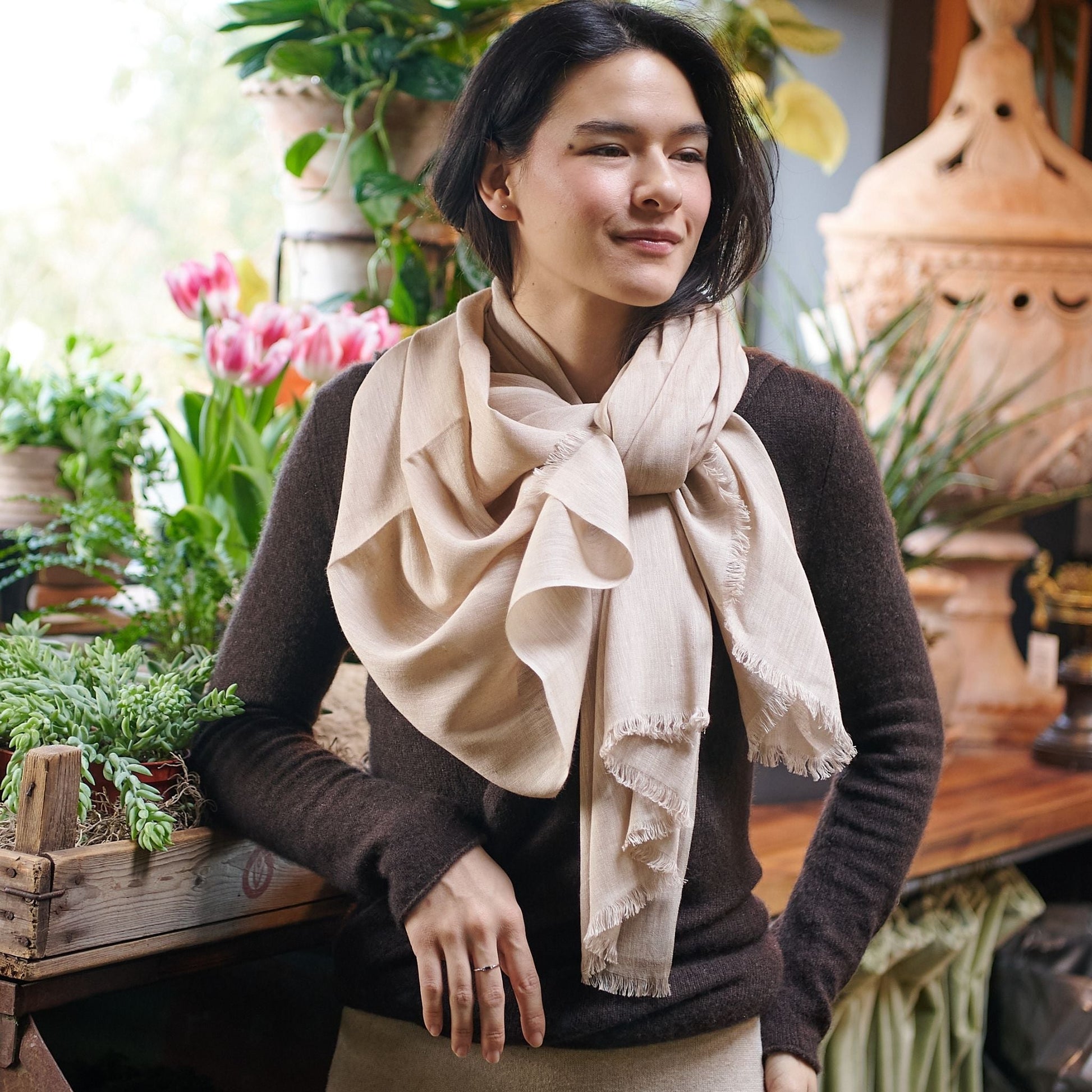 Oat Beige Neutral Hand Woven Soft Linen Silk Scarf styled elegantly on a model with plants in the background.