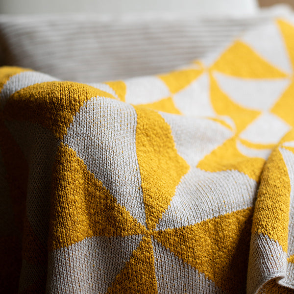 Close-up of a yellow and white patterned cotton blanket with triangle designs.