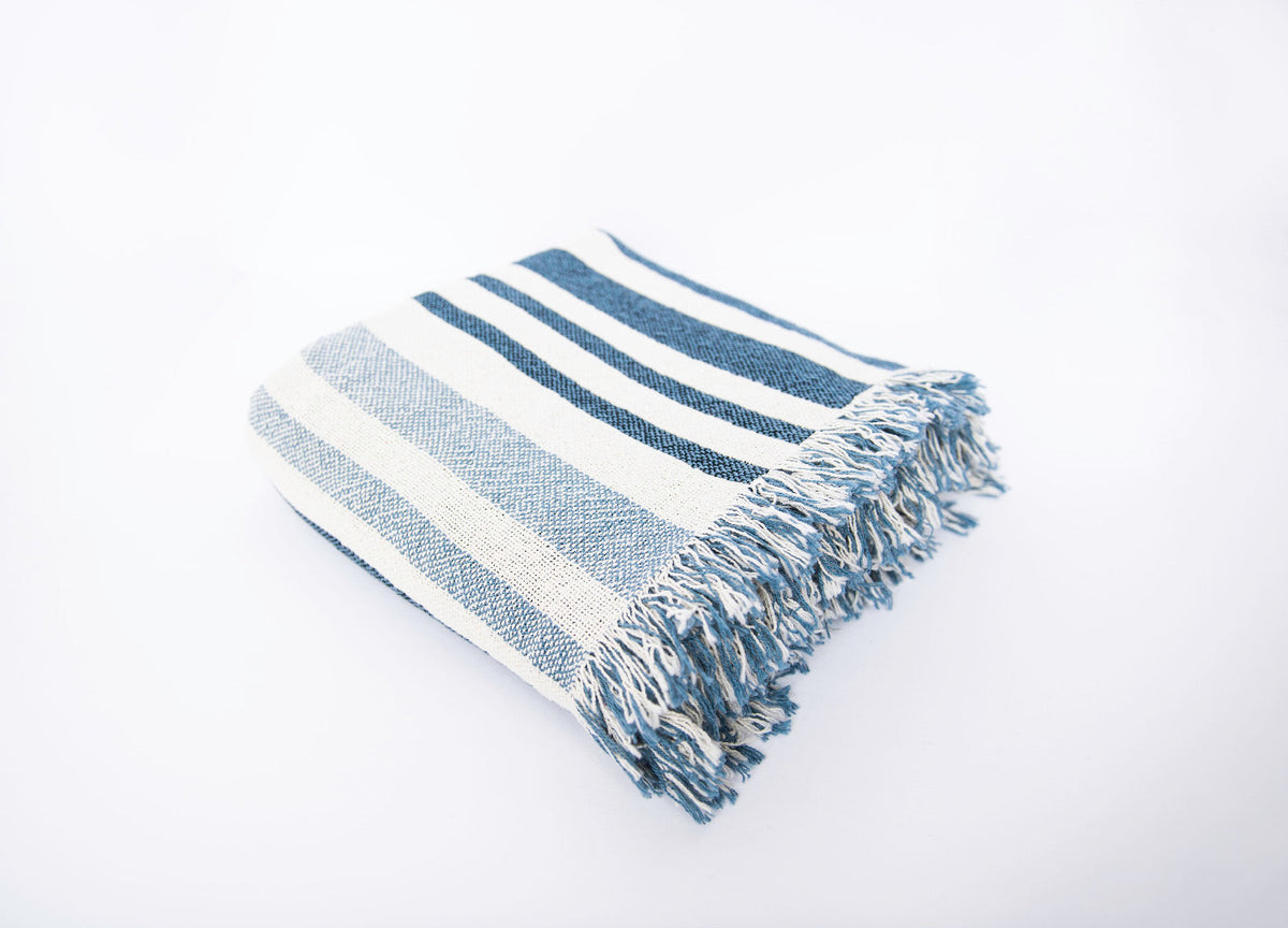 Folded Sutton Delft blue and cream striped woven throw blanket on a light background