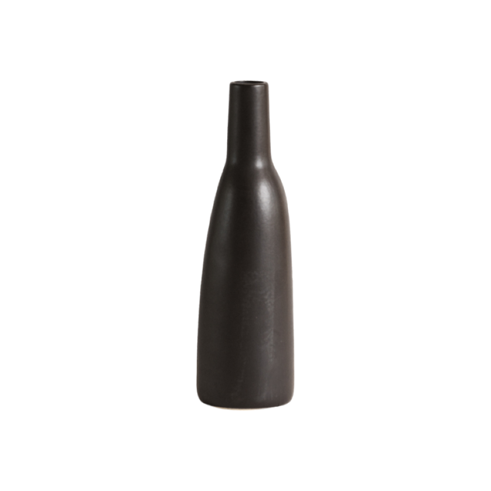 A white stoneware carafe with a narrow neck and a matte finish, displayed against a neutral background with a dry plant to the side.