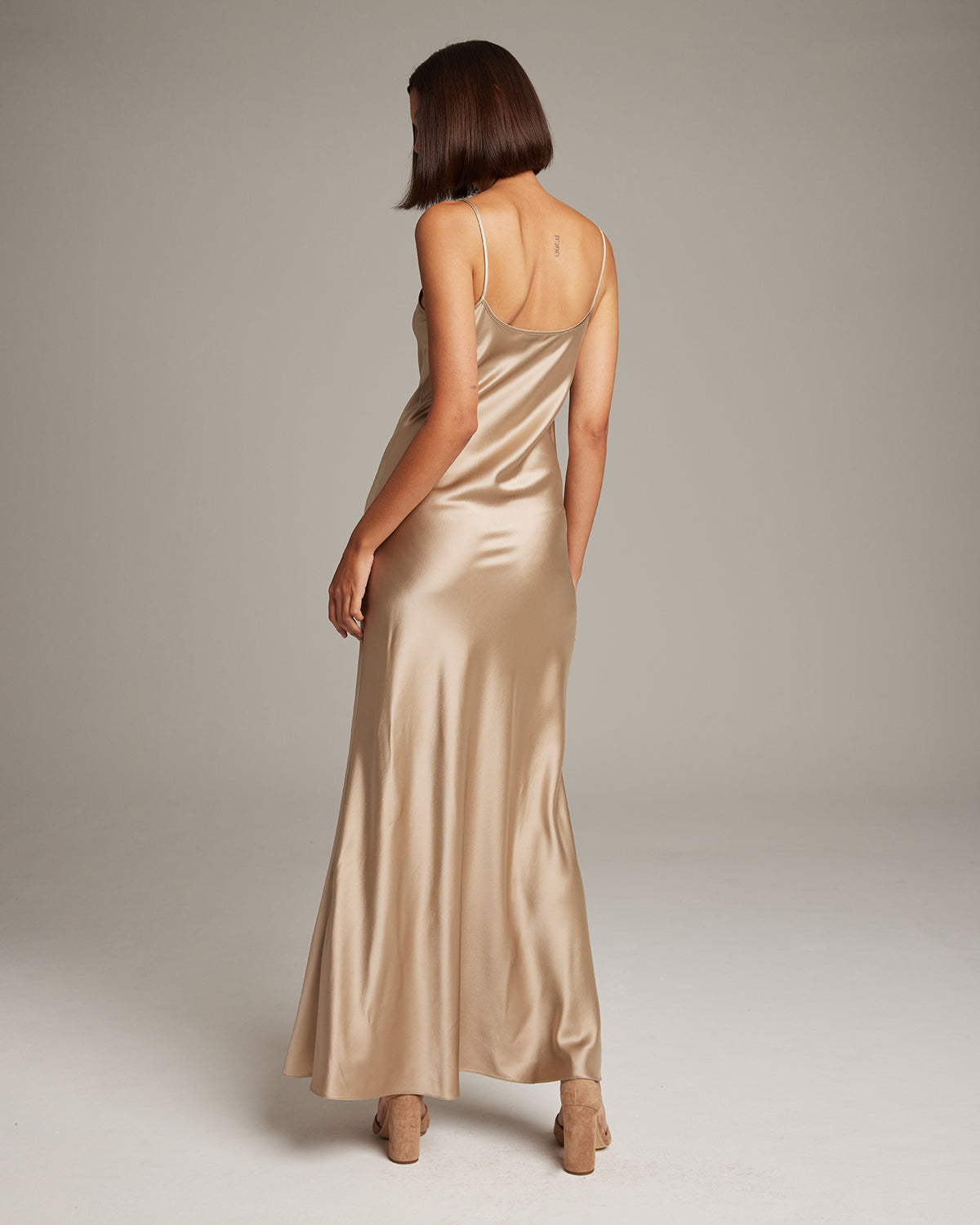 Model wearing a Liquid Silk Slipdress in champagne color, showing the back view.