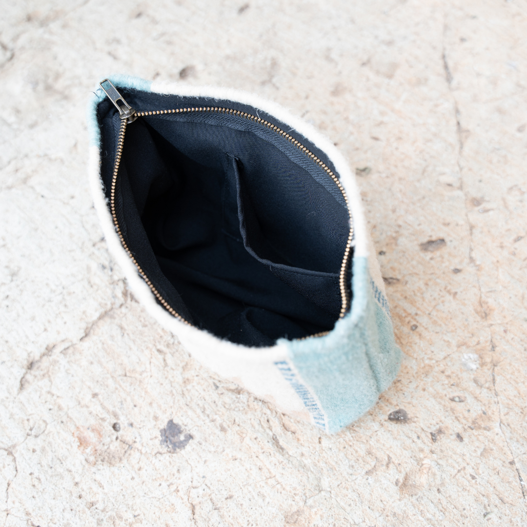 Interior view of andwoven pouch with abstract Zapotec lightning design in rose and blue tones, featuring internal pocket; ideal for use as a makeup bag, wallet, or tote organizer.