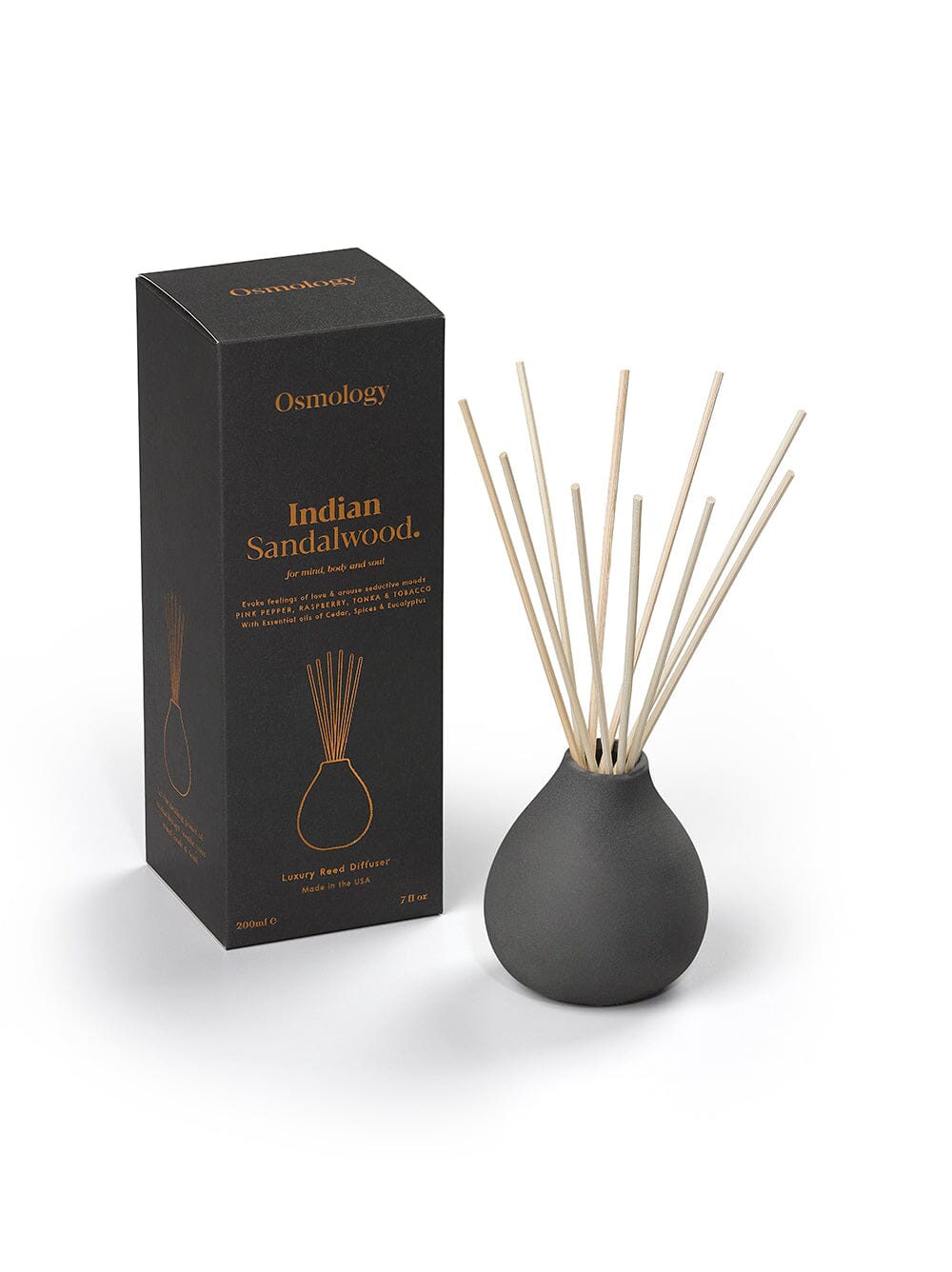 Osmology diffuser pot and bunched up reeds next to product packaging on a yellow-cream background
